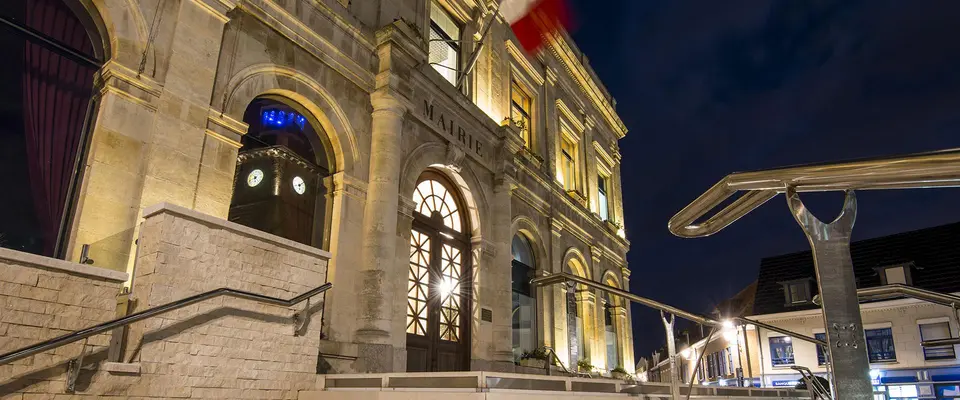 La façade de l’hôtel de ville éclairée à la tombée de la nuit.